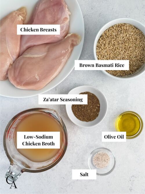 Chicken breasts, olive oil, za'atar seasoning, brown basmati rice, salt and chicken broth in containers on a counter.