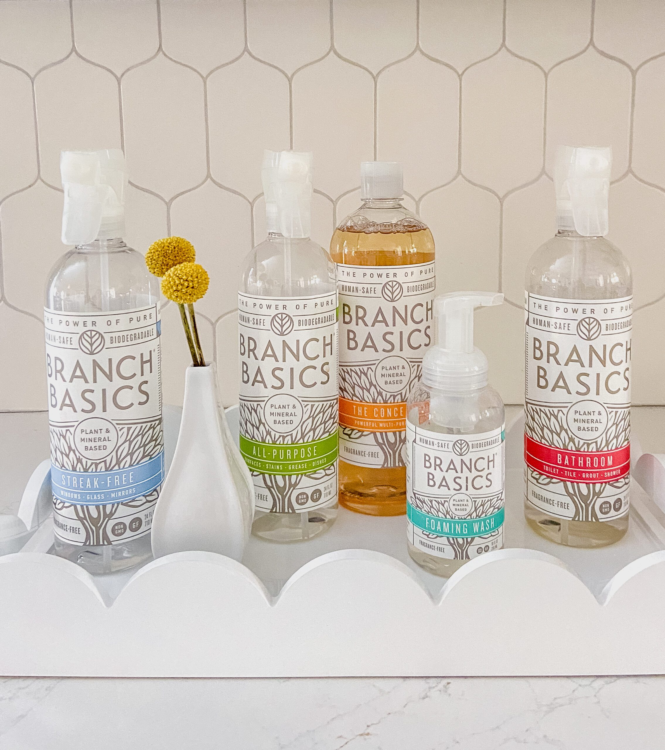 Spray bottles of home cleaners on a white tray.