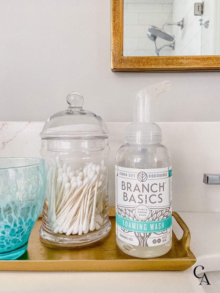 A bottle of hand soap and a glass canister of cotton swabs.