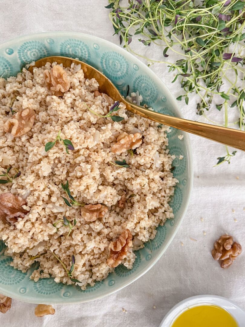 Millet and walnuts in a turquoise bowl with a gold spoon.