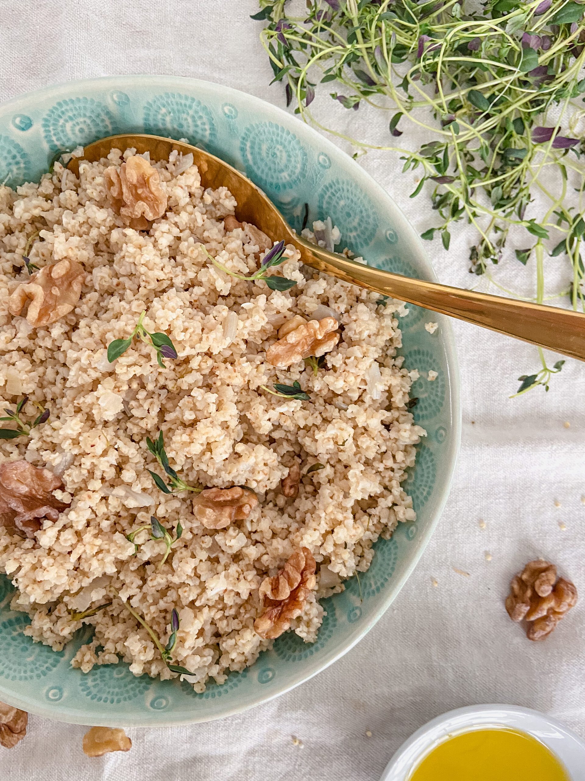 Millet and walnuts in a turquoise bowl with a gold spoon.