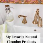 A bottle of hand soap next to a gold faucet on a sink.