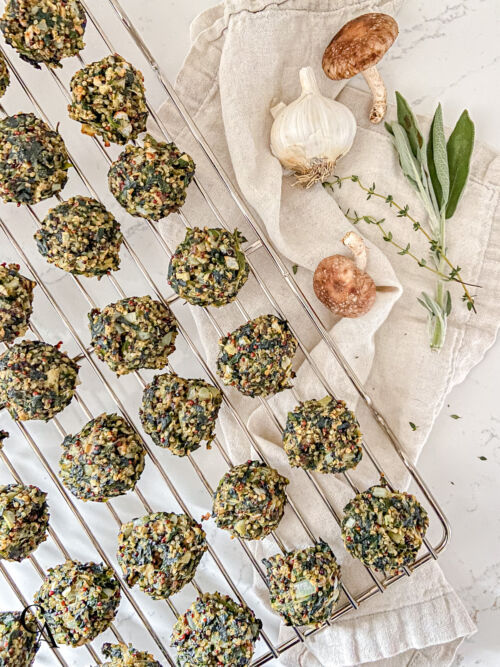 Cooked spinach balls on a cooling rack next to a linen napkin.