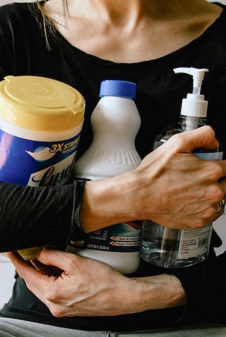 A woman holding bottles of traditional household cleaning products.