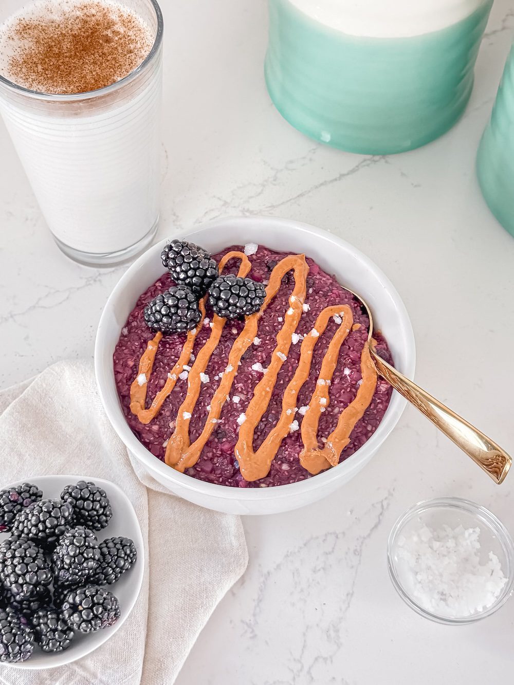 A bowl of peanut butter and jelly oatmeal with a gold spoon.