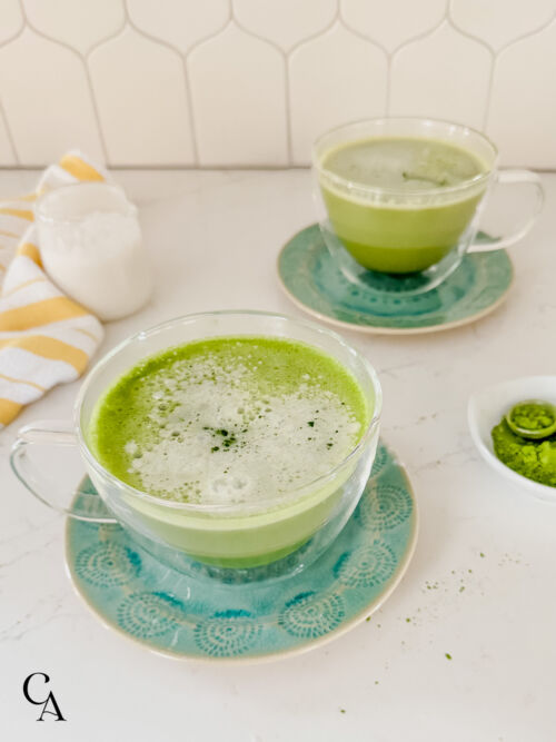 Two green beverages in front of a white backsplash.