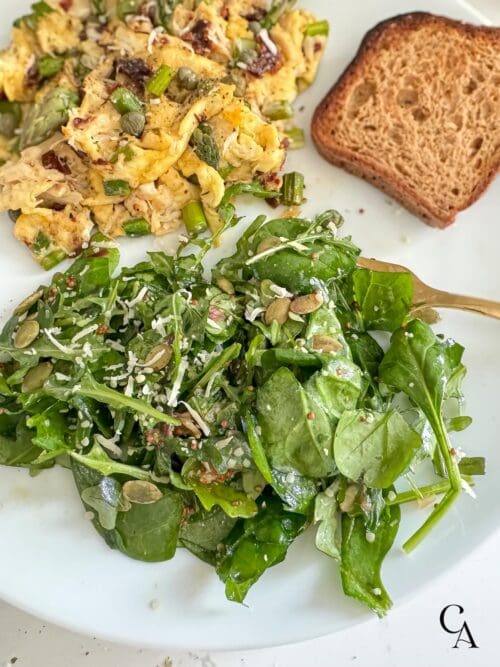 A green salad with scrambled eggs and toast.