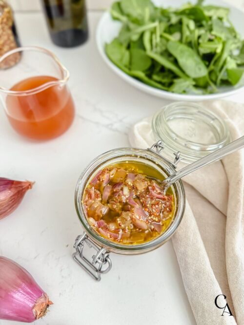 A glass jar of shallot and mustard vinaigrette.