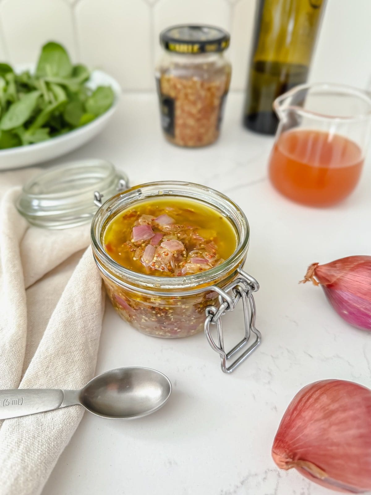 A small jar of mustard vinaigrette with shallots.