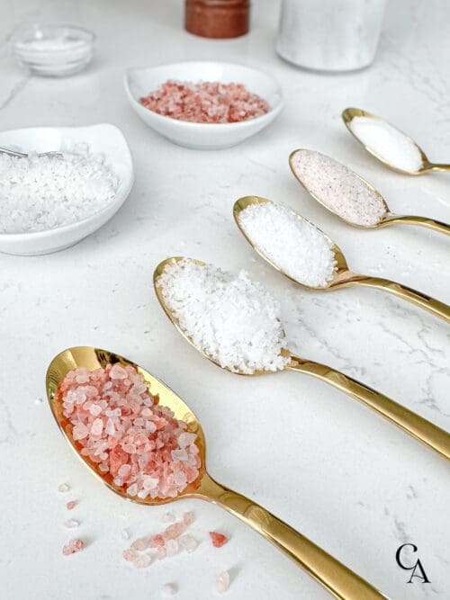 Gold spoons with a scoop of the best salt for cooking.