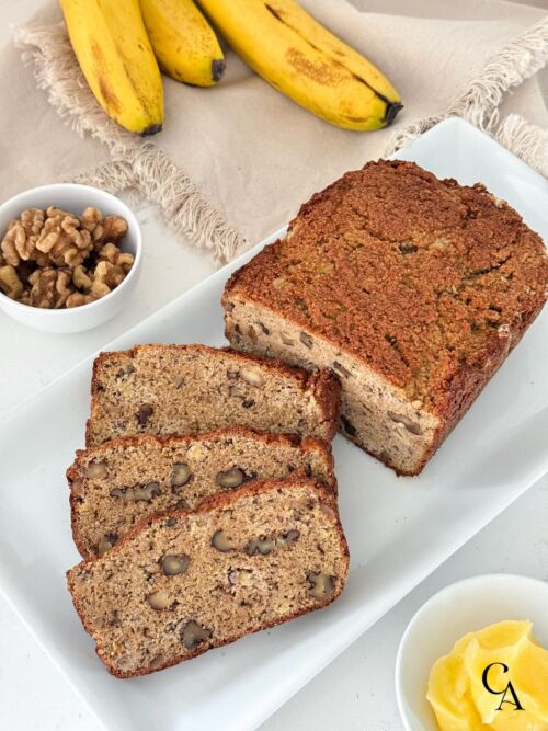 Sliced gluten-free banana bread with walnuts and a small bowl of ghee.