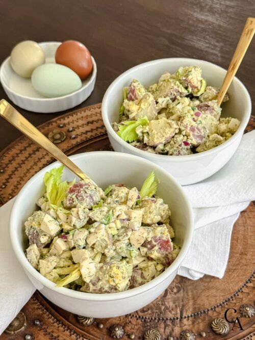 Bowls of simple potato salad with dill and gold forks.