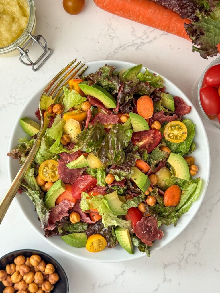 A bowl of salad with turkey bacon, lettuce, and tomato.