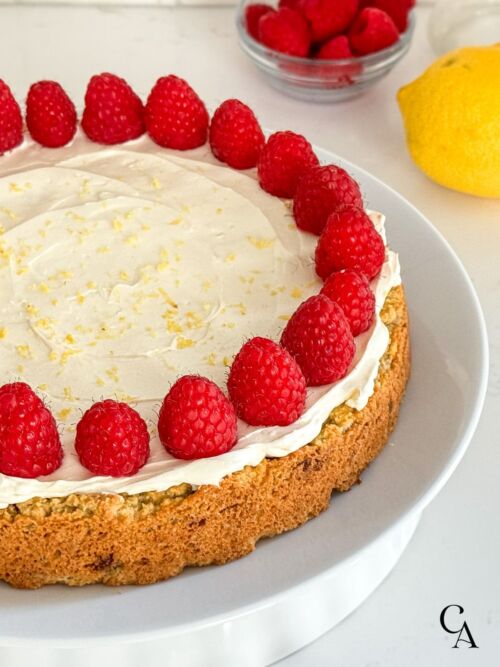 A cake with cream cheese frosting, fresh berries, and lemon zest.