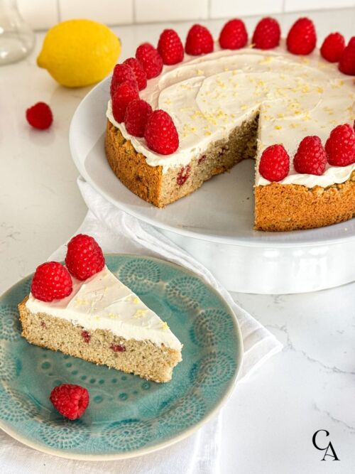 A lemon raspberry cake with a slice removed.
