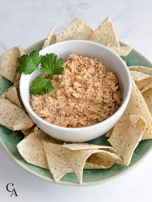 A bowl of tortilla chips with dip in the middle.