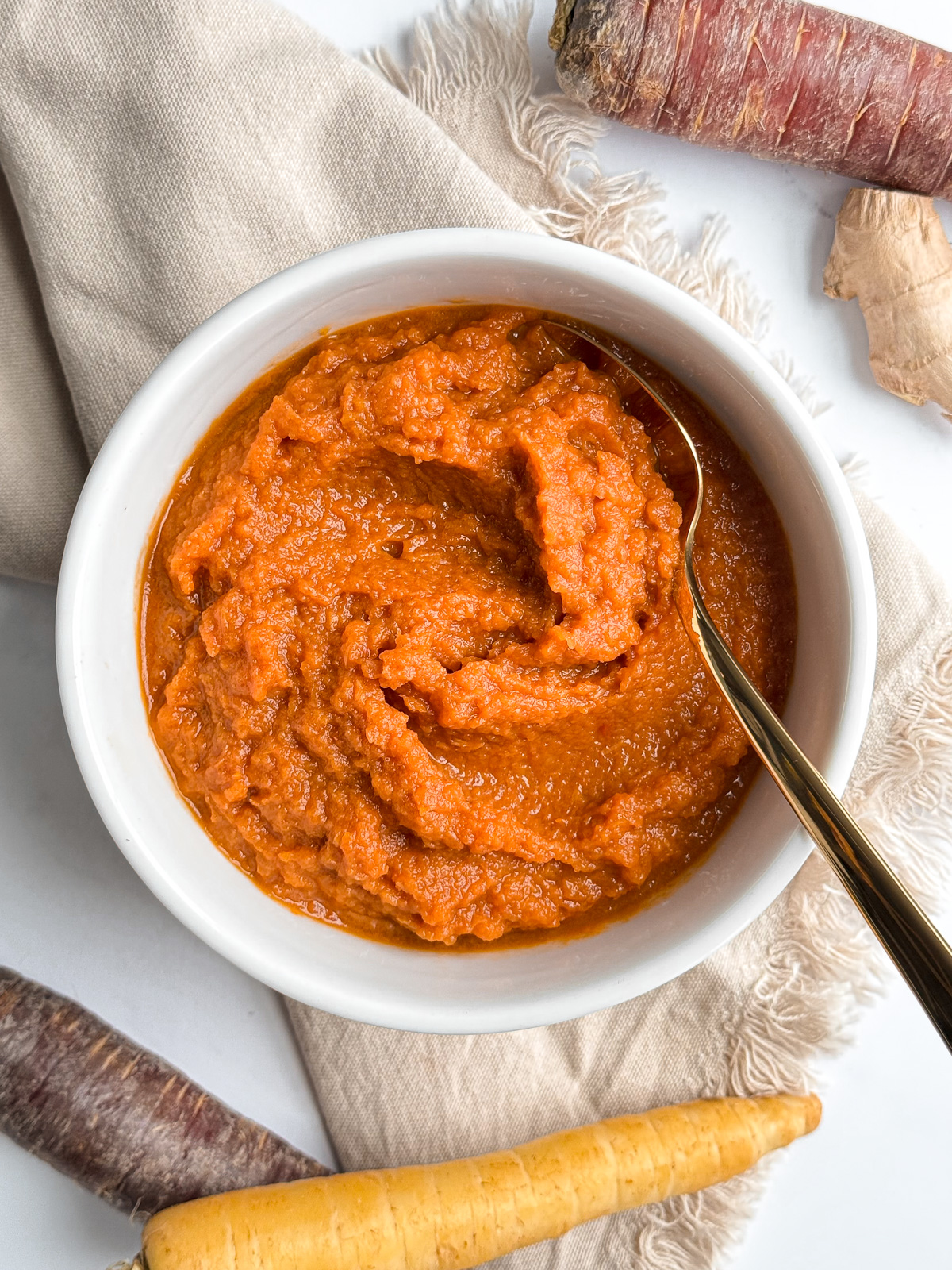 A bowl of carrot purée with fresh ginger on a linen napkin.