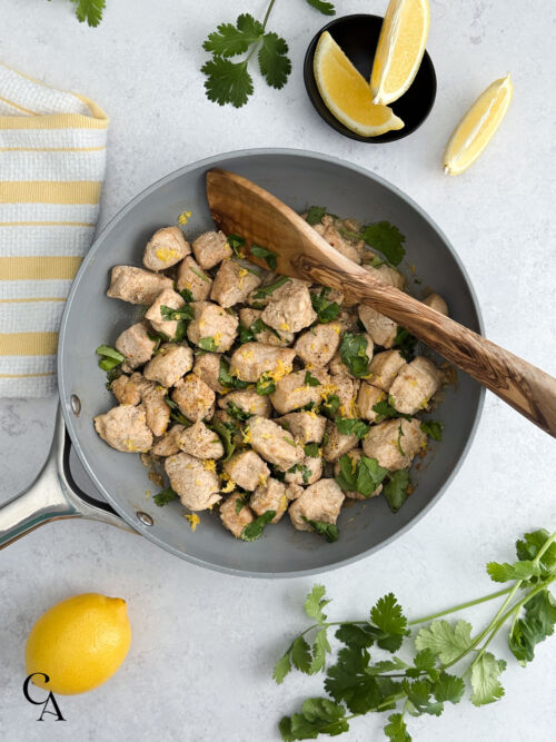 A pan of chicken tenders with lemon zest and chopped cilantro.