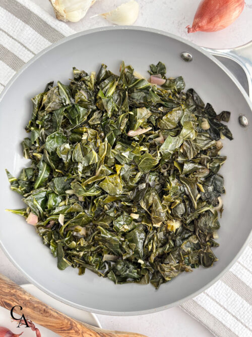 A pan of collards on a white an grey striped kitchen towel.