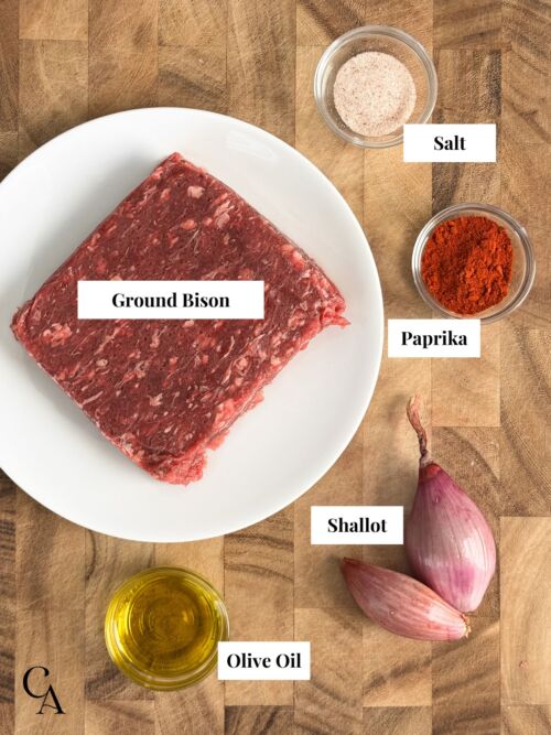 A plate of raw meat, and small bowls of ingredients.