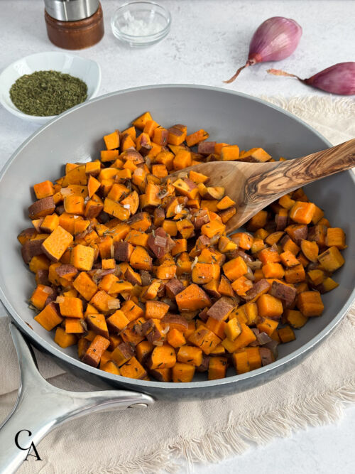 Diced sweet potatoes with salt, pepper, and thyme on a light surface.