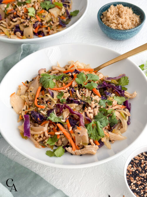 Close-up of turkey egg roll bowl with red cabbage, carrots, cilantro, bamboo shoots, and sesame seeds in a white bowl.