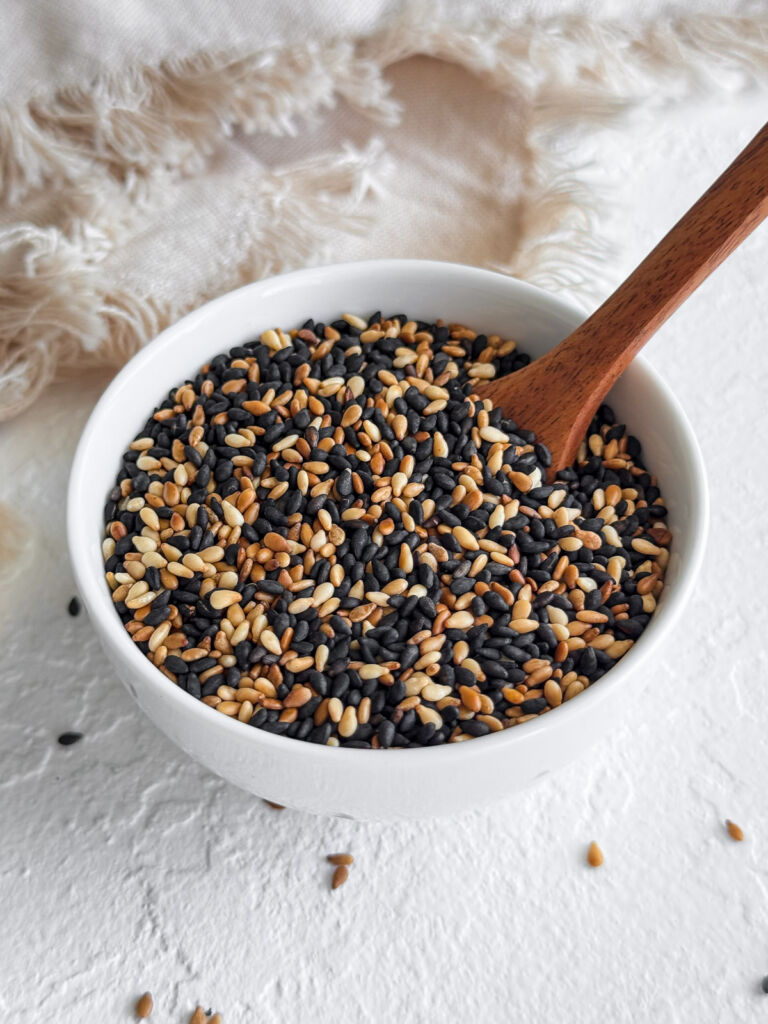 A bowl of toasted black and white sesame seeds sitting in front of a linen napkin.