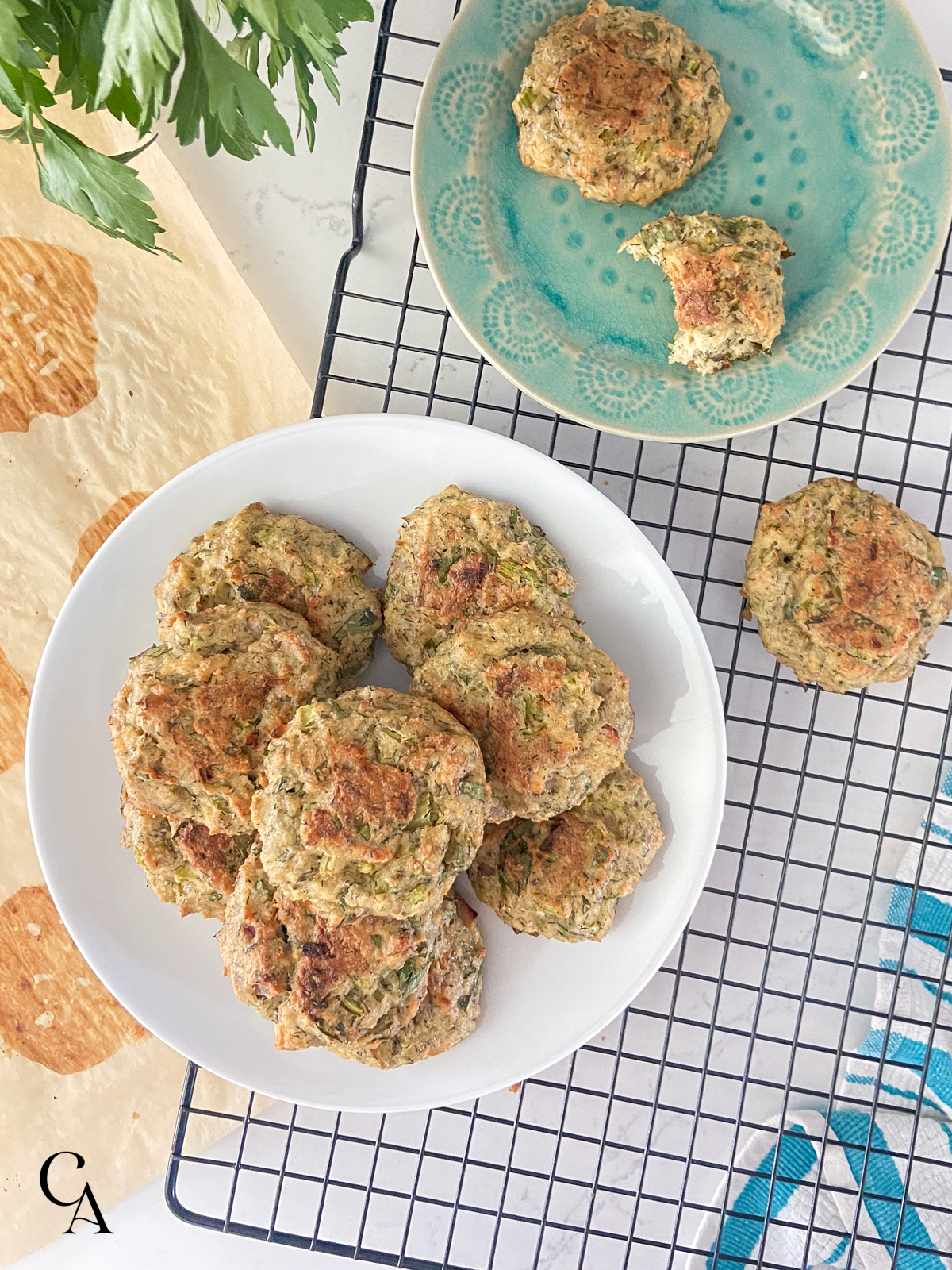 Two plates of canned salmon patties sitting on a wire cooling rack over a white counter.