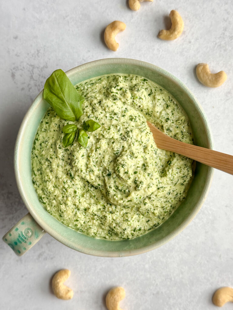 A bowl of cashew pesto with a wooden spoon.