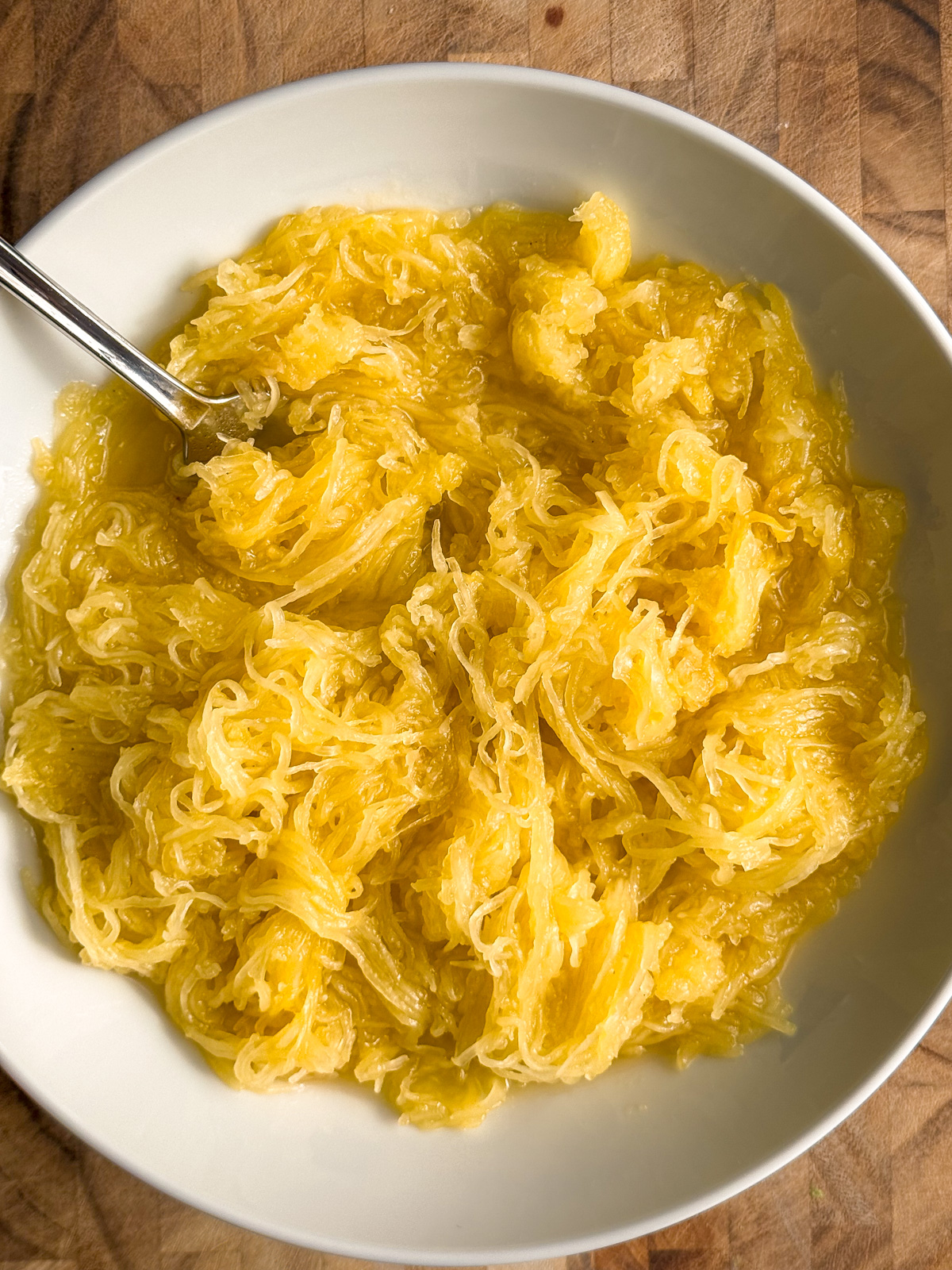 A bowl of cooked spaghetti squash pasta with a silver fork.