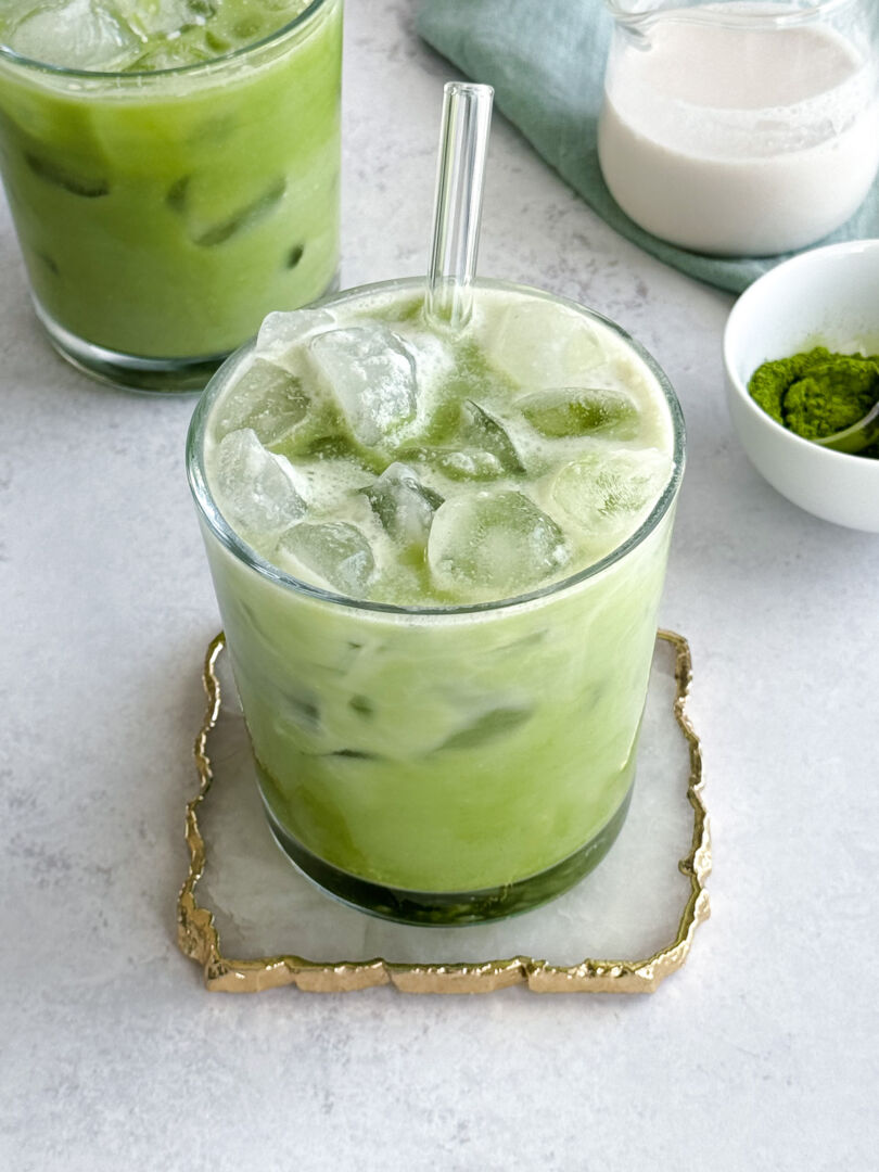 Green beverage served over ice cubes in a clear drinking glass.