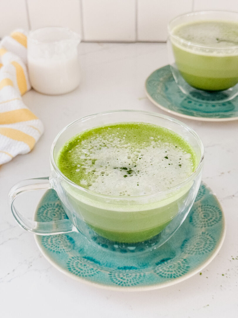 Two clear glass mugs full of matcha latte beverages
