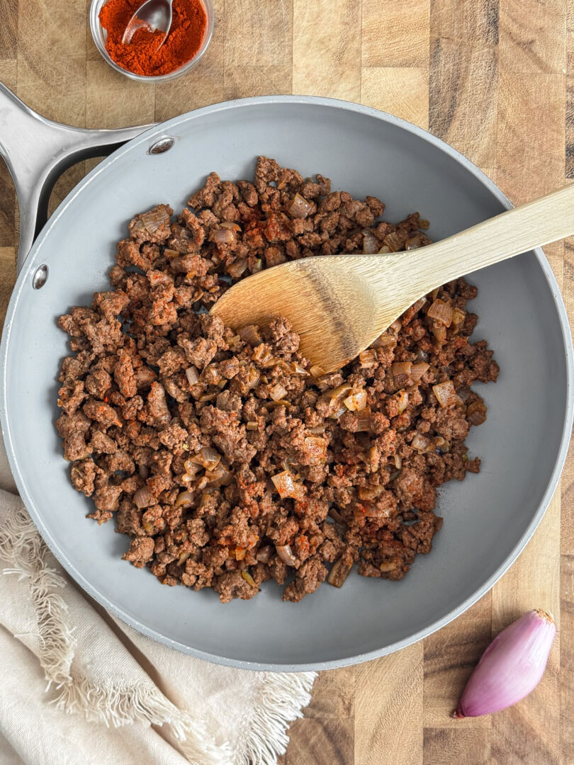 Overhead view of cooked ground bison in a gray skillet.