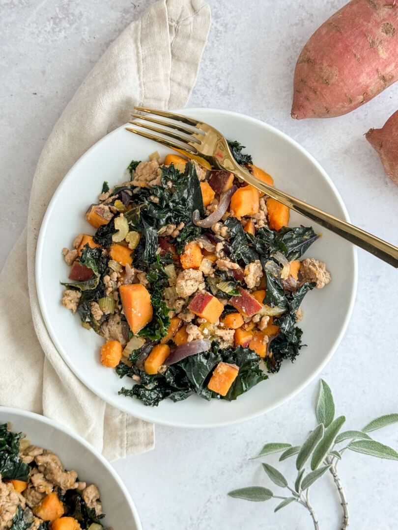 Overhead view of cooked ground turkey in a bowl with diced sweet potatoes and chopped kale.