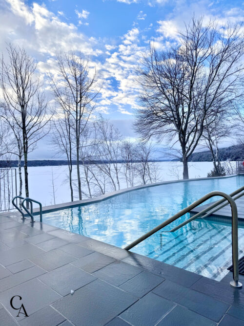 A heated pool next to a frozen lake in winter.