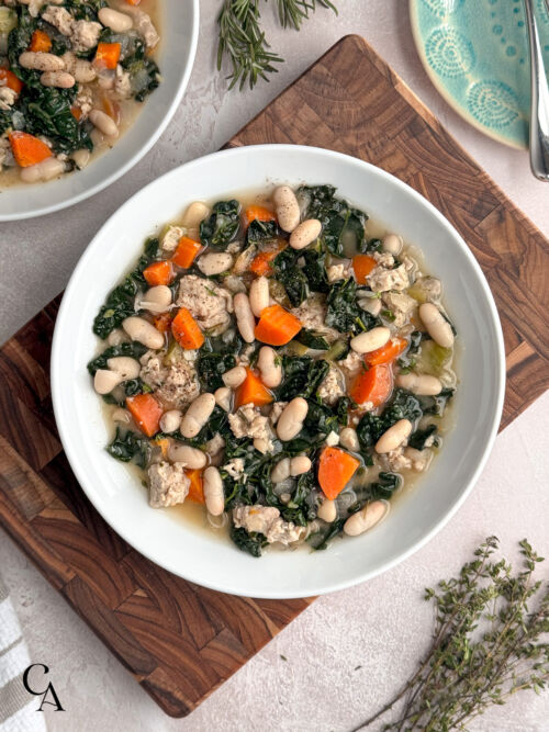 Overhead view of bowls of a Mediterranean-style bean soup with greens, carrots, and ground chicken.
