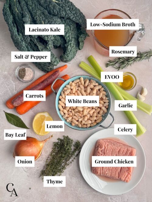 Ingredients for a Mediterranean-style bean and kale soup, arranged on a countertop.